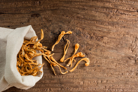 A hessian bag on a wooden table filled with cordyceps